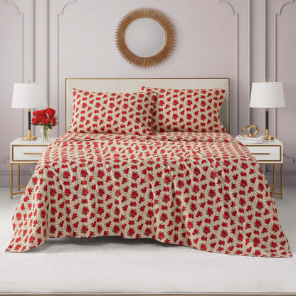 A neatly made bed features the Printed Microfiber Sheet Set in a cream and red floral pattern with matching pillows, flanked by white nightstands and lamps, beneath a round sunburst mirror in a modern room.