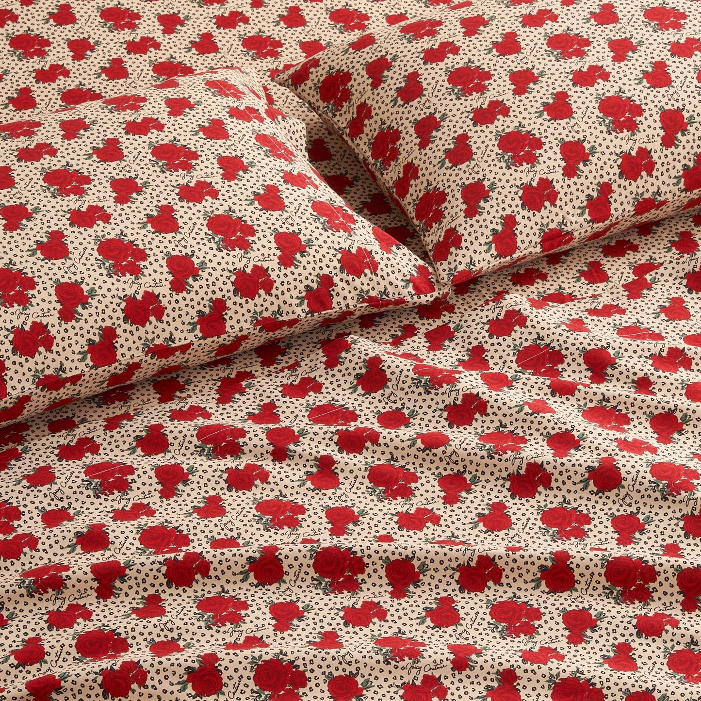 Close-up of a bed with matching pillowcases and sheets from the Printed Microfiber Sheet Set, featuring a beige background with red floral prints and small black dotted accents for a luxurious look.