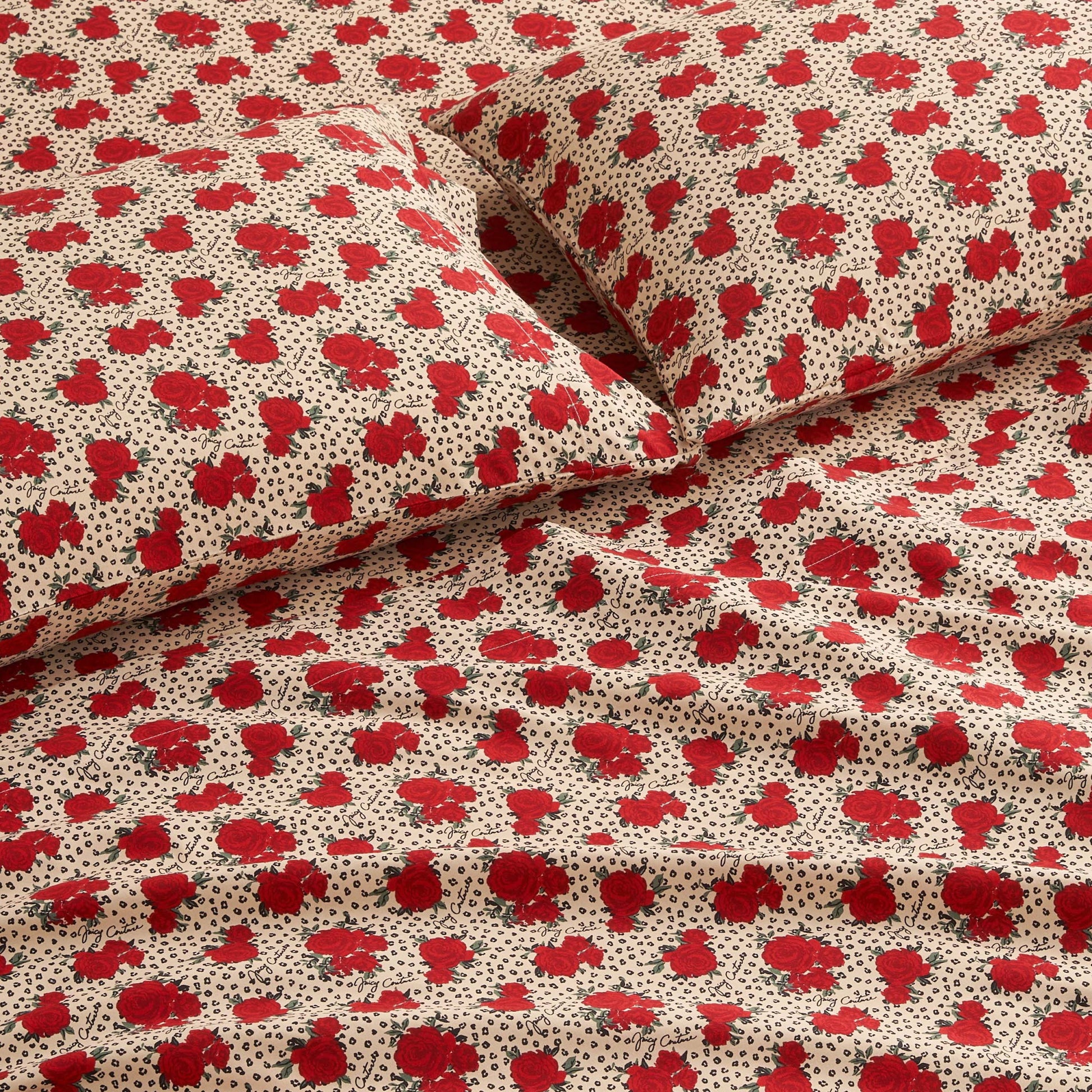 Close-up of a bed with matching pillowcases and sheets from the Printed Microfiber Sheet Set, featuring a beige background with red floral prints and small black dotted accents for a luxurious look.
