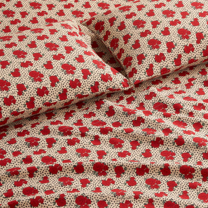 Close-up of a bed with matching pillowcases and sheets from the Printed Microfiber Sheet Set, featuring a beige background with red floral prints and small black dotted accents for a luxurious look.