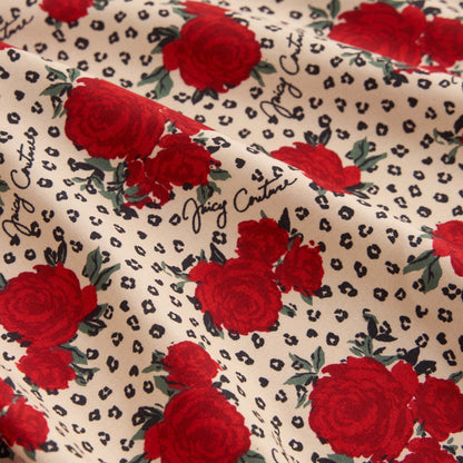 The Printed Microfiber Sheet Set features cream fabric with red roses, small black animal print spots, and "Juicy Couture" in cursive—an ideal choice to bring luxurious Juicy Couture style to your bedding.