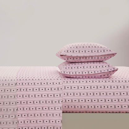 Two pink pillows on a bed with matching sheets, all displaying a black geometric and X pattern from the Printed Microfiber Sheet Set, create an elegant look against a plain light gray wall.