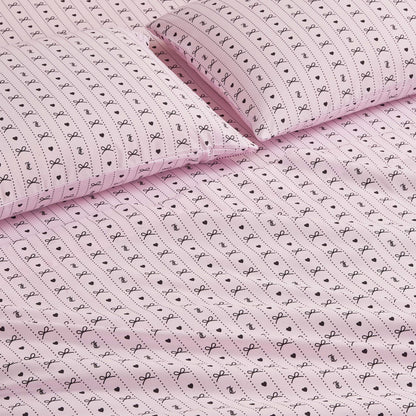 The Printed Microfiber Sheet Set features pink sheets and pillowcases adorned with small black bows, dots, and lines for a playful, delicate touch—perfect for adding charm and luxury to your bedroom décor.