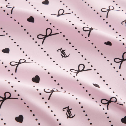 The Printed Microfiber Sheet Set features a light pink design with black hearts, dots, bows, and intertwined “A” and “C”. Its softly wrinkled texture offers a gentle, wavy look for chic bedroom style.