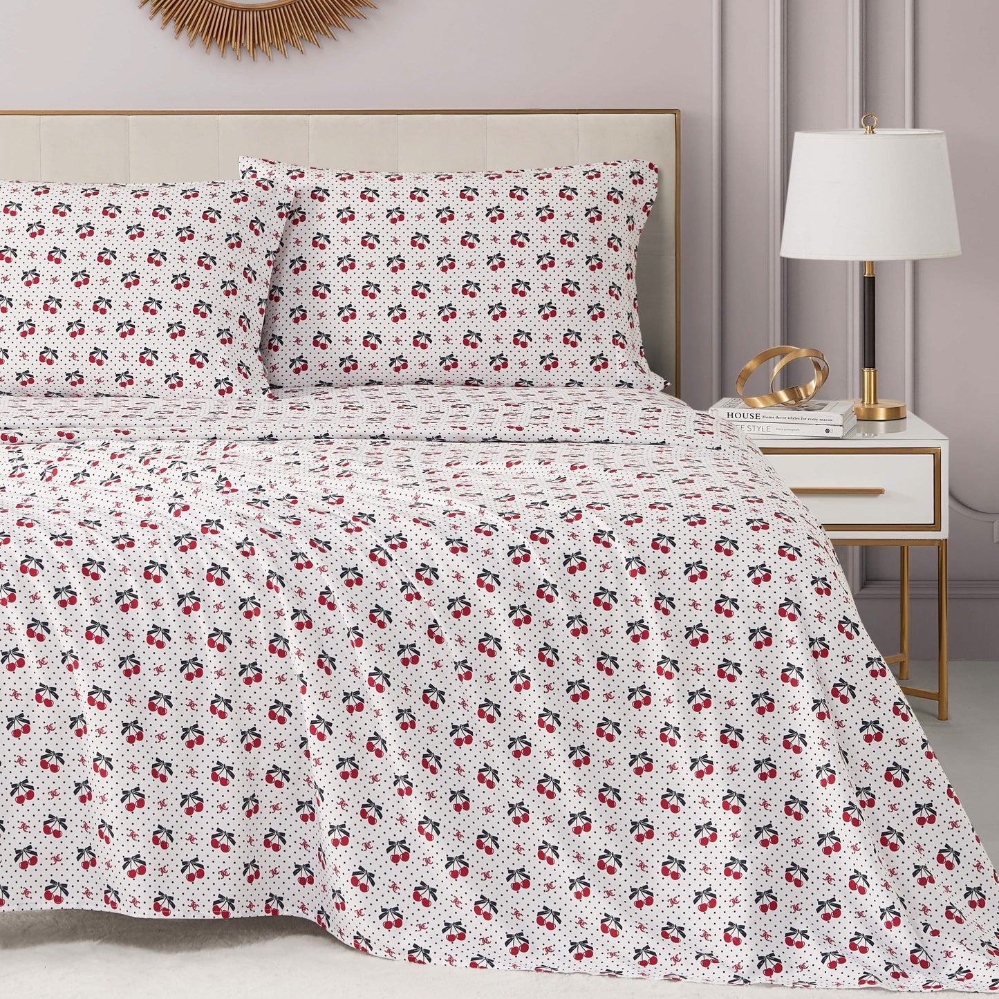 A neatly made bed features the Printed Microfiber Sheet Set with a subtle red and black floral design, adding a luxe touch. Beside it, a modern nightstand holds a lamp, books, and gold decor. The room is finished with soft neutral walls.