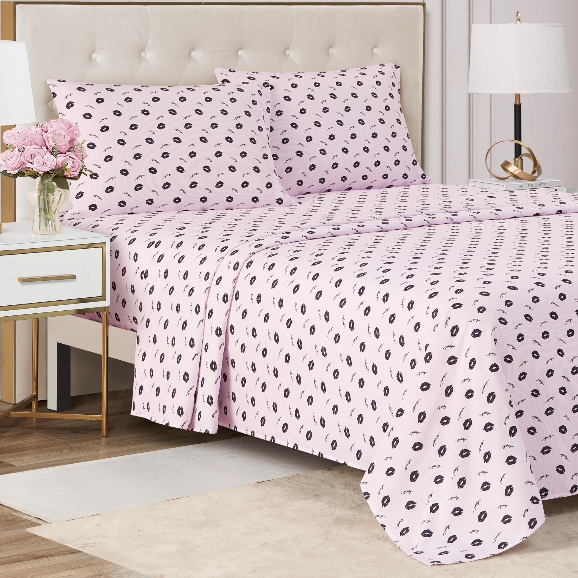 A neatly made bed with the Printed Microfiber Sheet Set, featuring a light pink base and small black leaf pattern, beside a white nightstand with flowers and a lamp—modern style meets luxury in the perfect bedroom update.