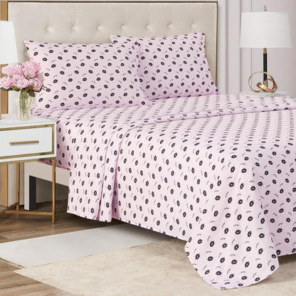 A neatly made bed with the Printed Microfiber Sheet Set, featuring a light pink base and small black leaf pattern, beside a white nightstand with flowers and a lamp—modern style meets luxury in the perfect bedroom update.