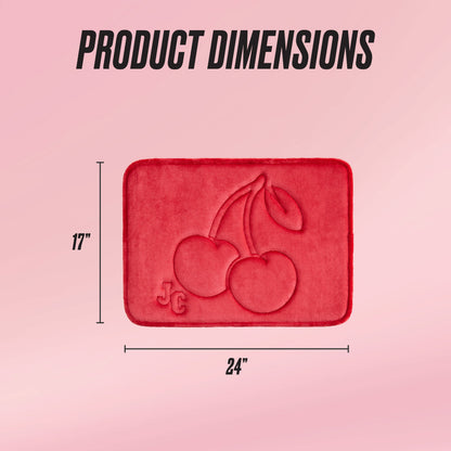 A red rectangular Quilted Memory Foam Bath Mat with embossed cherries and JC initials is shown on a pink background. Black text above reads PRODUCT DIMENSIONS. This luxury rug measures 17 x 24 inches.