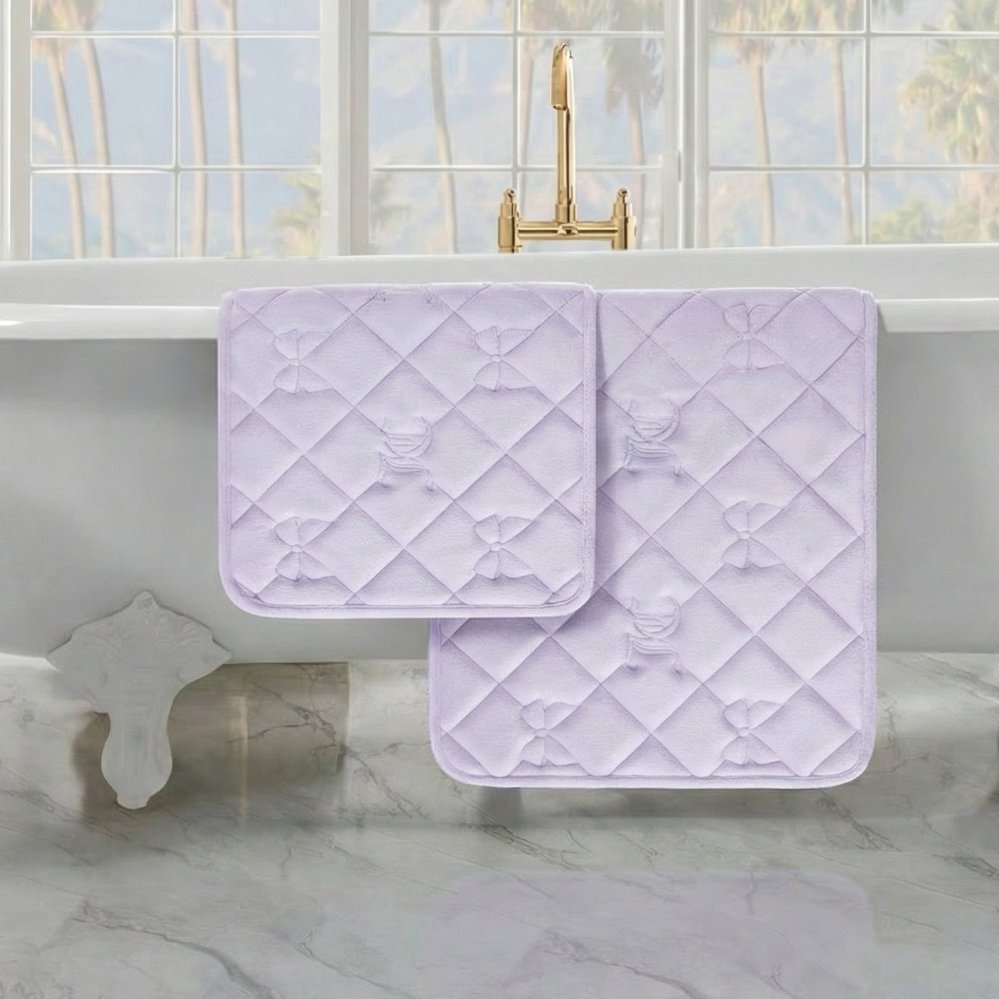 Two Quilted Memory Foam Bath Mats are draped over a white bathtub in a bright bathroom with marble floors and large windows.