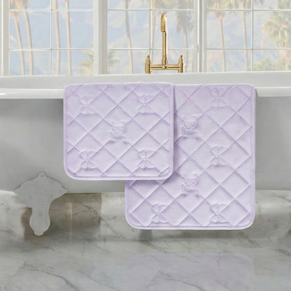 Two Quilted Memory Foam Bath Mats are draped over a white bathtub in a bright bathroom with marble floors and large windows.