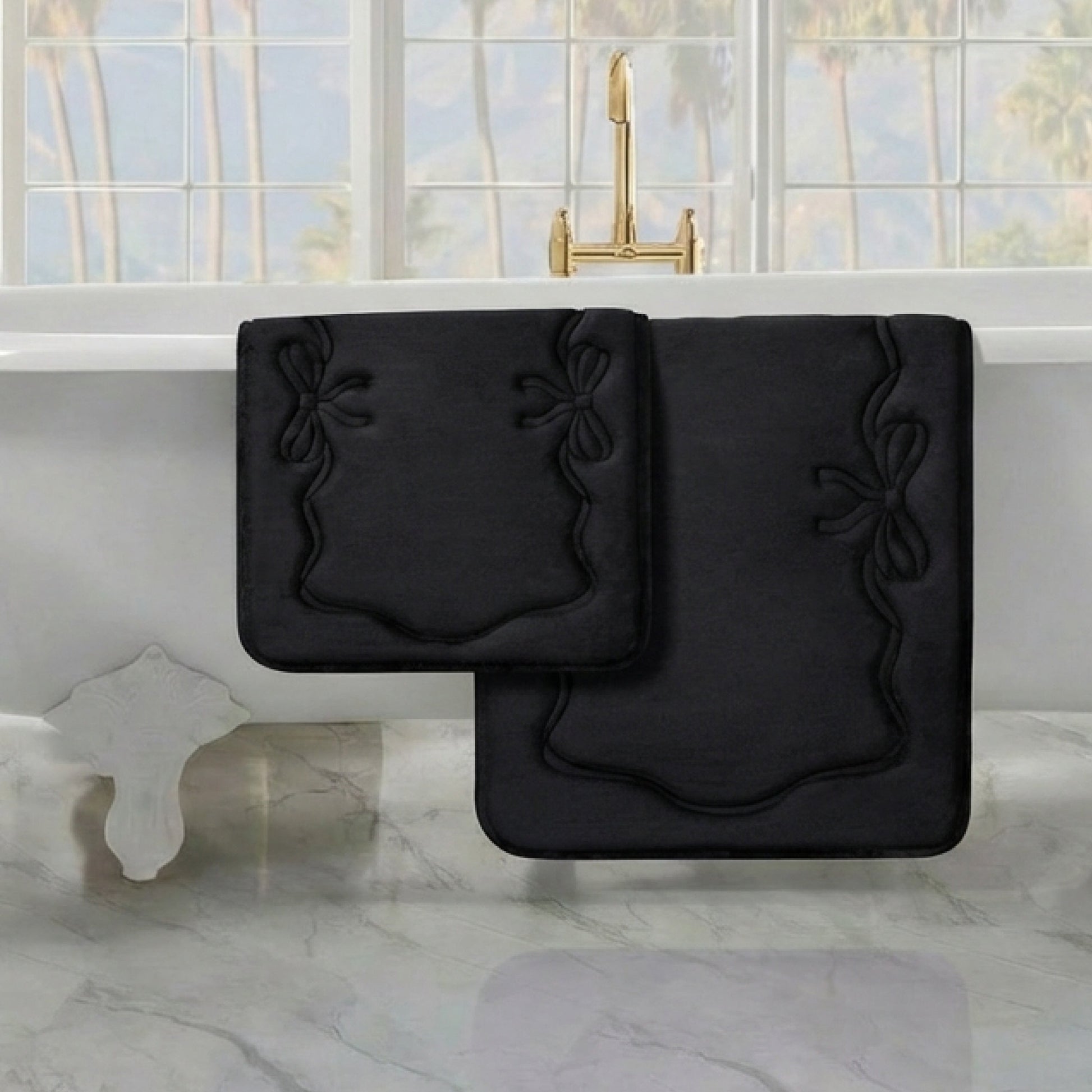 Two Quilted Memory Foam Bath Mats from the 2-piece set are placed on a marble floor near a white bathtub with gold fixtures, set by a large window overlooking scenic views.