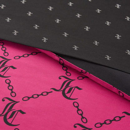Folded fabric from the Link Printed Bed in a Bag Bedding Set displays two patterns: a black top layer with small white chain and monogram motifs, and a pink bottom layer featuring large black chains and monogram designs.