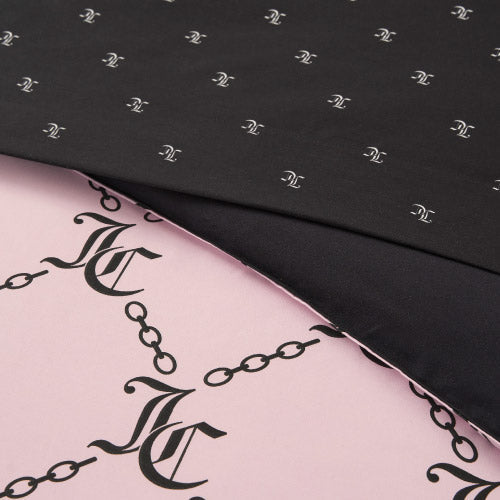 Close-up of two overlapping fabrics from the Link Printed Bed in a Bag Bedding Set: the top black layer shows a small white pattern, while the pink fabric below displays a bold black chain and interlocking JC monogram design.