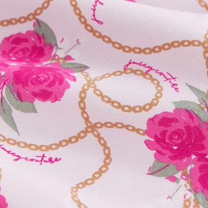 Close-up of pink rose prints and gold chain patterns on the Microfiber Sheet Set With Extra Pillowcases. "Juicy Couture" appears in pink cursive among the designs, adding a touch of luxury bedding style.