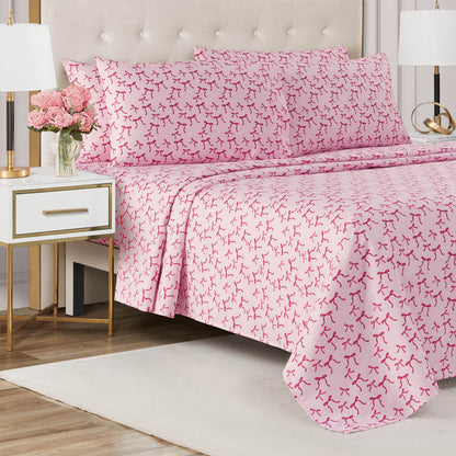 A neatly made bed with the Microfiber Sheet Set With Extra Pillowcases in pink and red abstract print sits by a white nightstand with a lamp and pink roses, accented by a beige tufted headboard and a light area rug for added luxury.