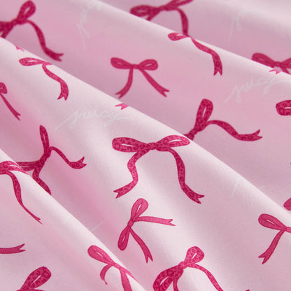 The Microfiber Sheet Set With Extra Pillowcases features light pink sheets with darker pink bows and subtle white "juicy" prints, crafted from soft microfiber that drapes beautifully for a playful touch to your bedding.