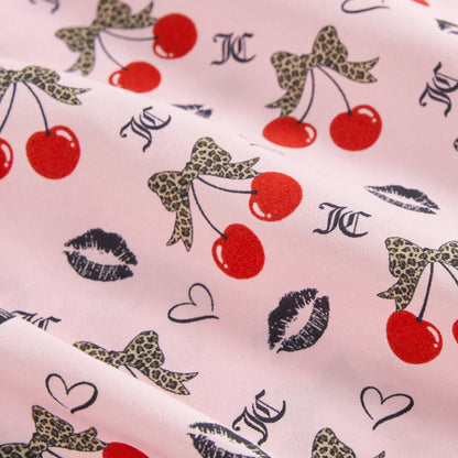The Printed Microfiber Sheet Set features pink fabric with red cherries, leopard print bows, black lips, hearts, and JC letters for a playful look. Enjoy soft folds and stylish luxury bedding in any room.