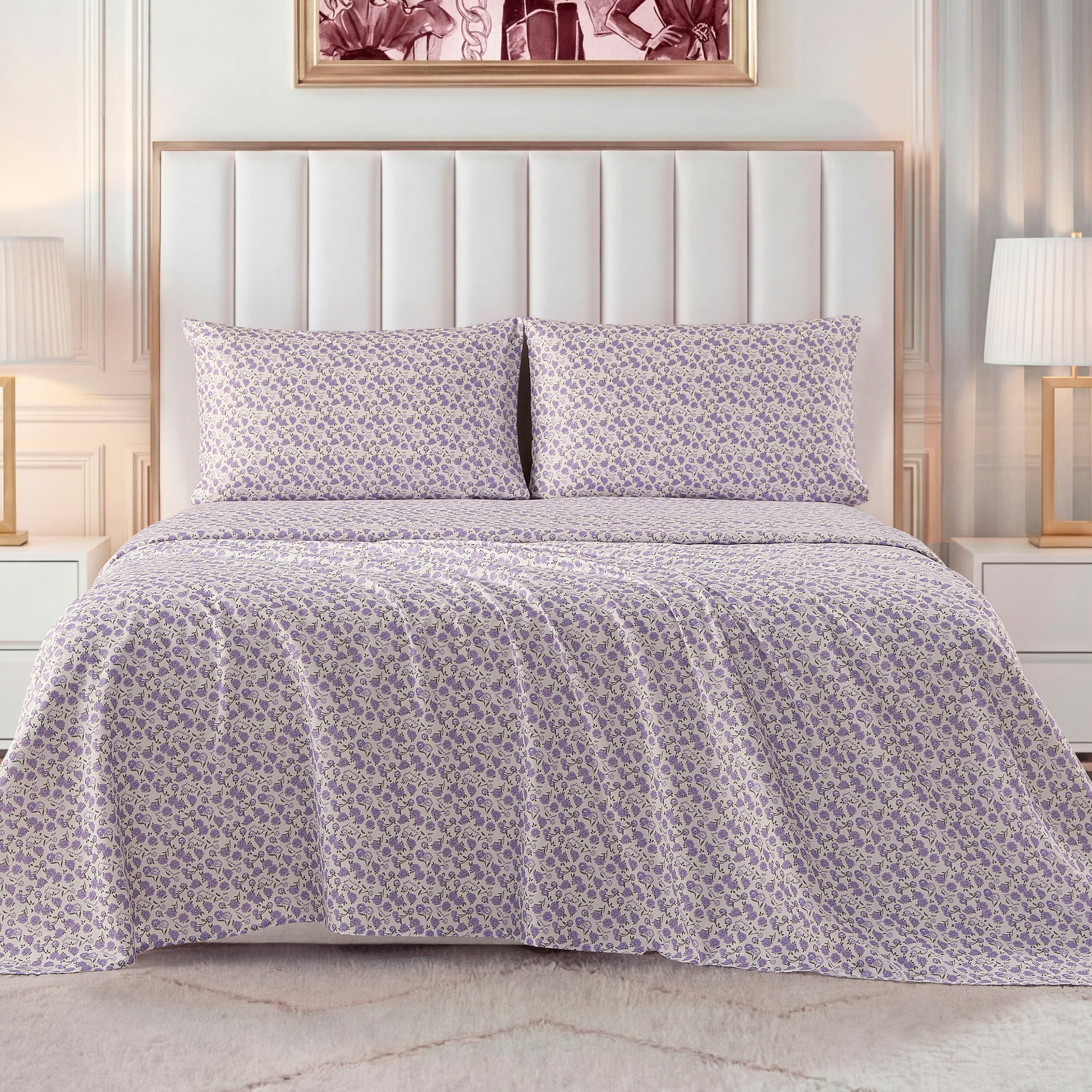 A neatly made bed with a white padded headboard features a light purple and white floral bedspread, matching pillows, and the Printed Microfiber Sheet Set. White nightstands and lamps sit beside the bed, with framed art displayed above.