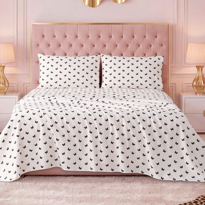 A neatly made bed with a pink tufted headboard and luxury bedding, including a white Printed Microfiber Sheet Set with a black butterfly pattern, flanked by white nightstands with lamps, in a pink-walled, elegant bedroom.
