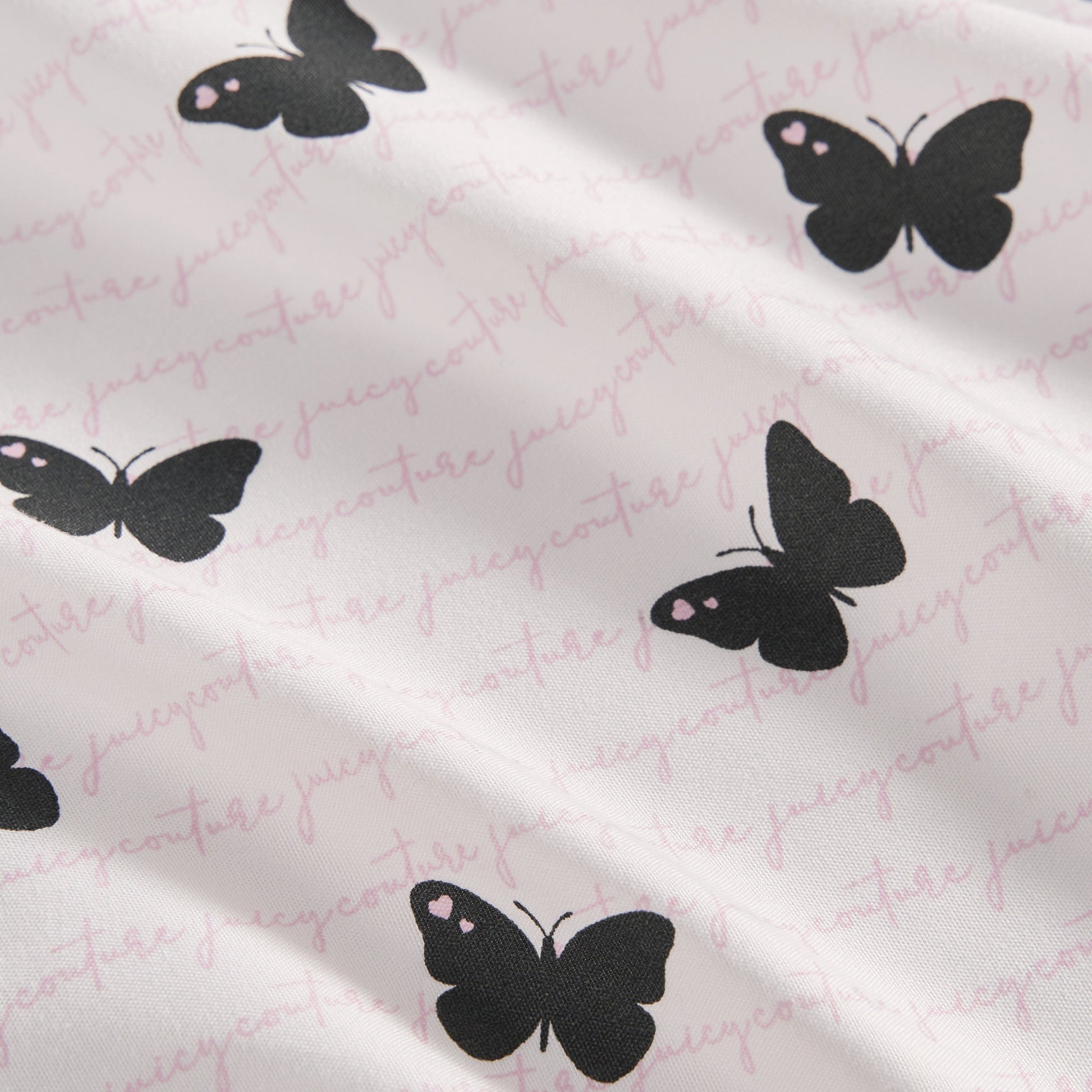 The Printed Microfiber Sheet Set features black butterfly designs and subtle pink Juicy Couture cursive text, bringing a touch of luxury to your bedding ensemble.