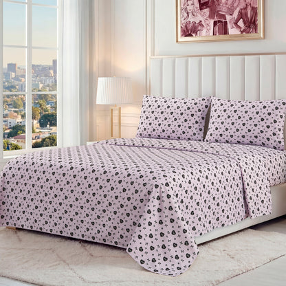 A neatly made bed with a Printed Microfiber Sheet Set in light pink and black floral pattern, two matching pillows, a padded white headboard, lamp, framed artwork, and a large window overlooking the city.
