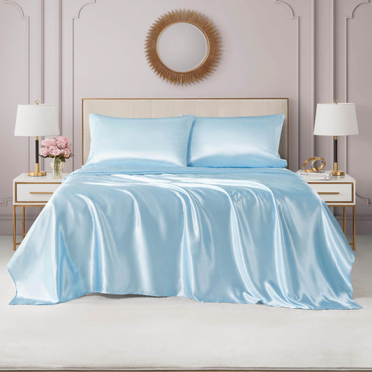 A bed with the Solid Satin Sheet Set and matching pillowcases sits between white nightstands with lamps and pink flowers, set against a pale pink paneled wall topped by a round mirror above the headboard.