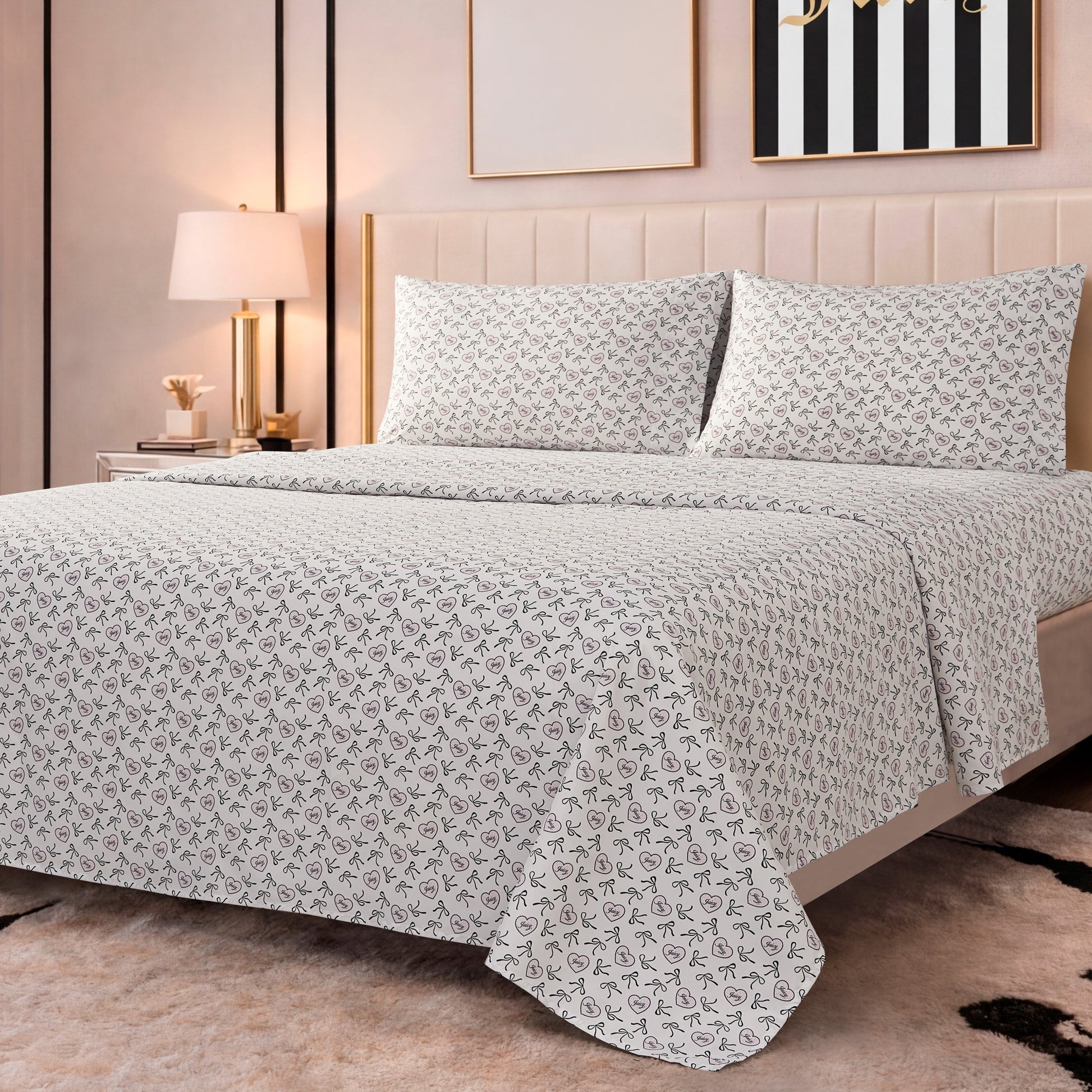 The Printed Microfiber Sheet Set features white sheets and pillowcases adorned with pink hearts, black bows, and "Juicy" text—a signature Juicy Couture design for a stylish bedroom update.