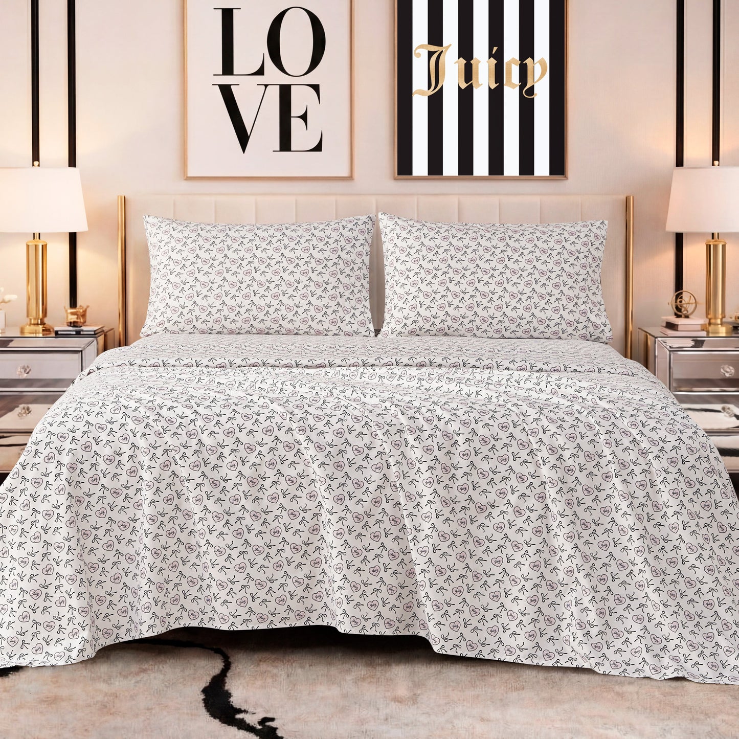 A neatly made bed features the Printed Microfiber Sheet Set in white and gray, flanked by mirrored nightstands and gold lamps. Behind the bed, two framed prints—one reading LOVE, the other Juicy—complete the luxurious look.
