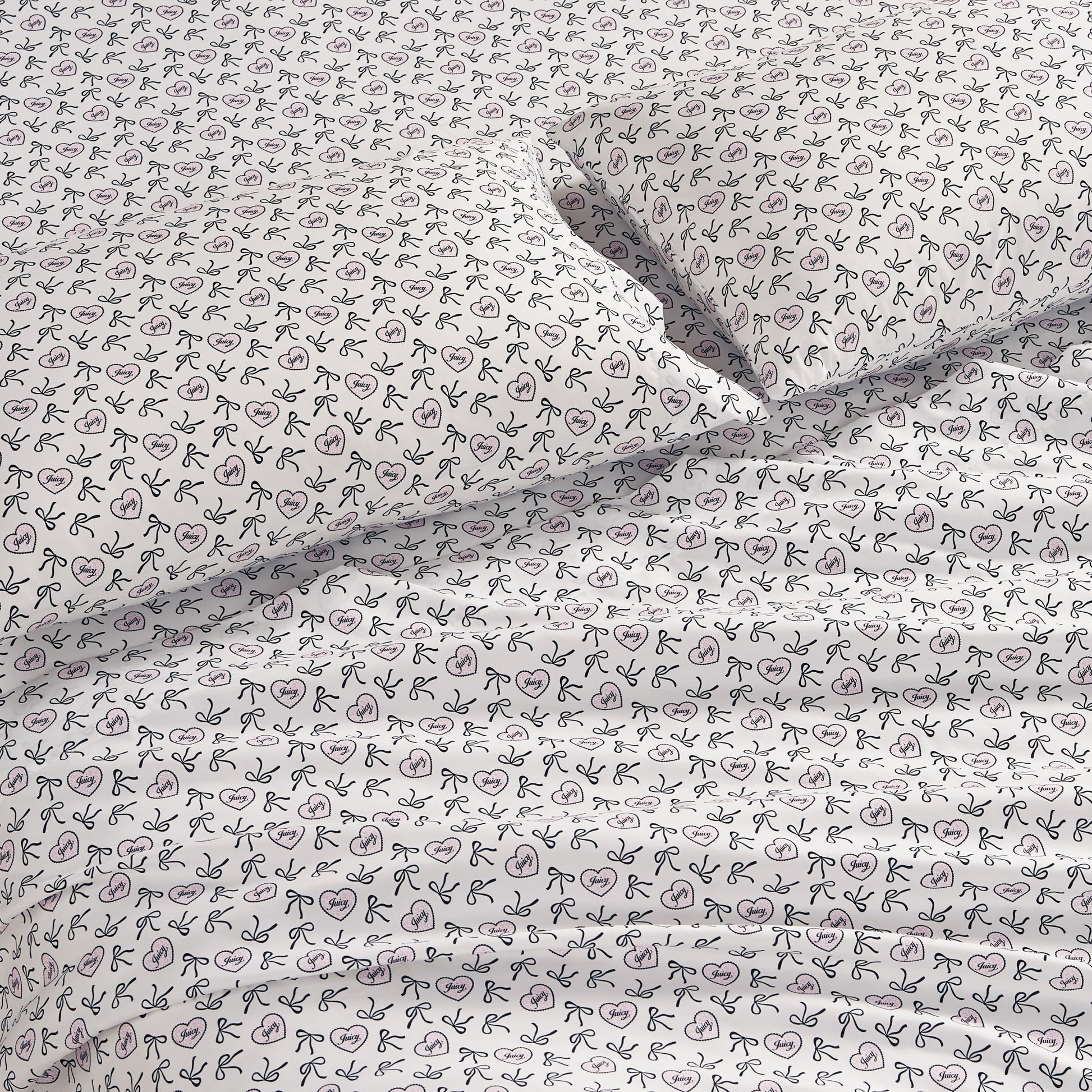White bedsheets and pillowcases with a simple black line bow pattern, neatly spread on the bed—a chic Printed Microfiber Sheet Set providing soft microfiber comfort.
