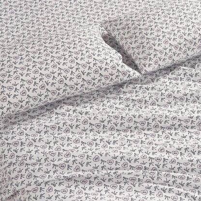 White bedsheets and pillowcases with a simple black line bow pattern, neatly spread on the bed—a chic Printed Microfiber Sheet Set providing soft microfiber comfort.
