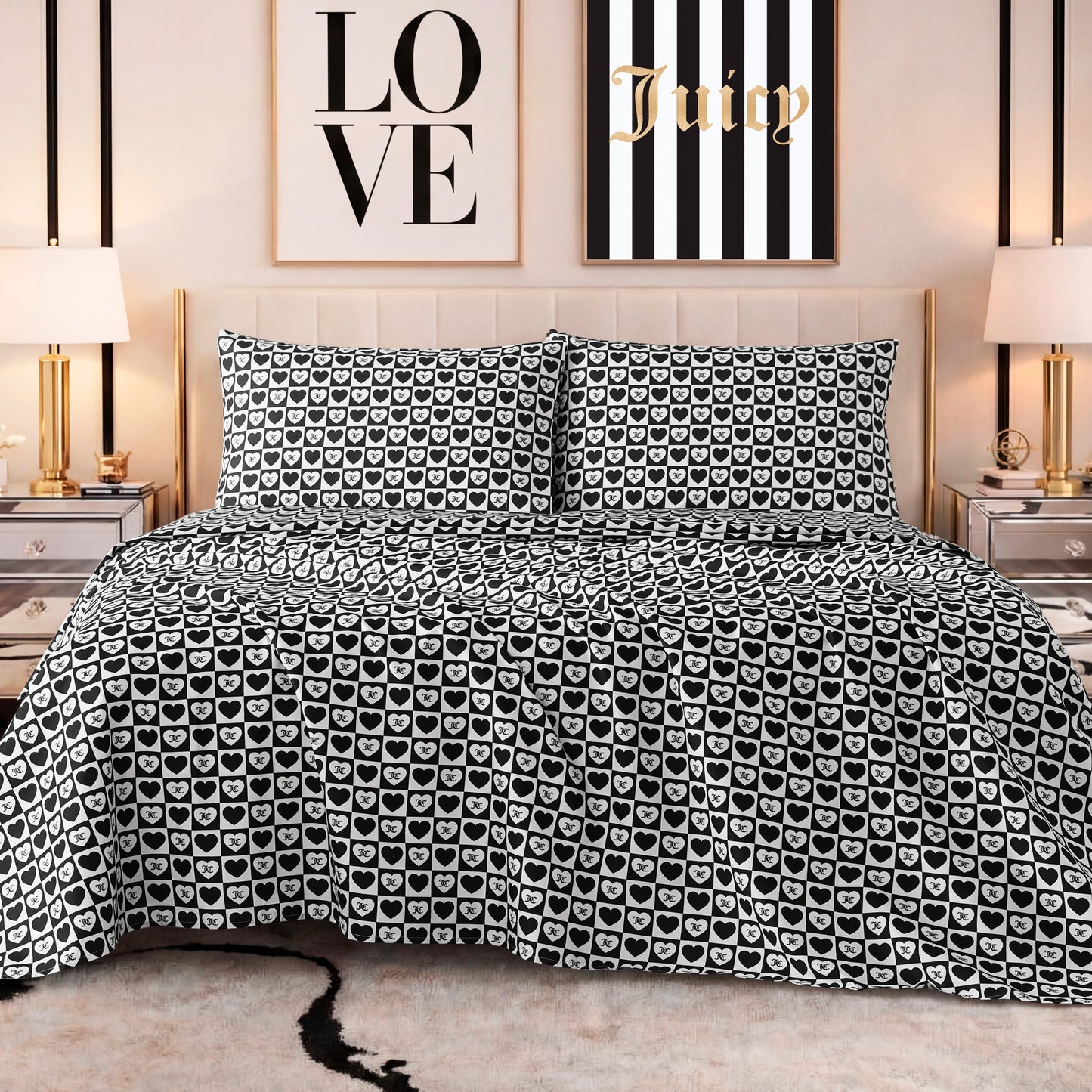 A stylish bedroom features a bed with a black and white heart-patterned comforter, matching pillows, a Printed Microfiber Sheet Set, gold lamps on mirrored nightstands, and LOVE and Juicy wall art above the headboard.