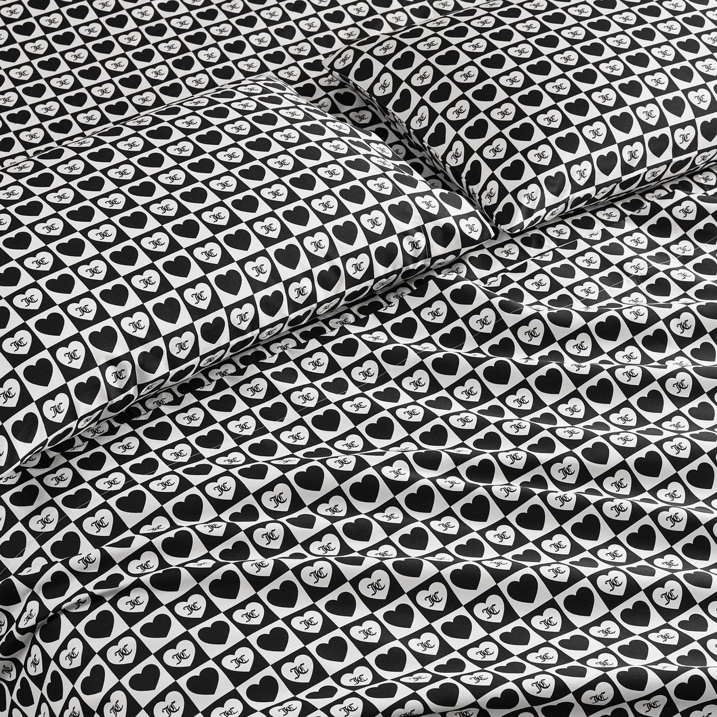 The Printed Microfiber Sheet Set features a bold black-and-white design with hearts and “NYC” text, creating a stylish look on the pillowcases and comforter—ideal for anyone who loves luxury bedding.