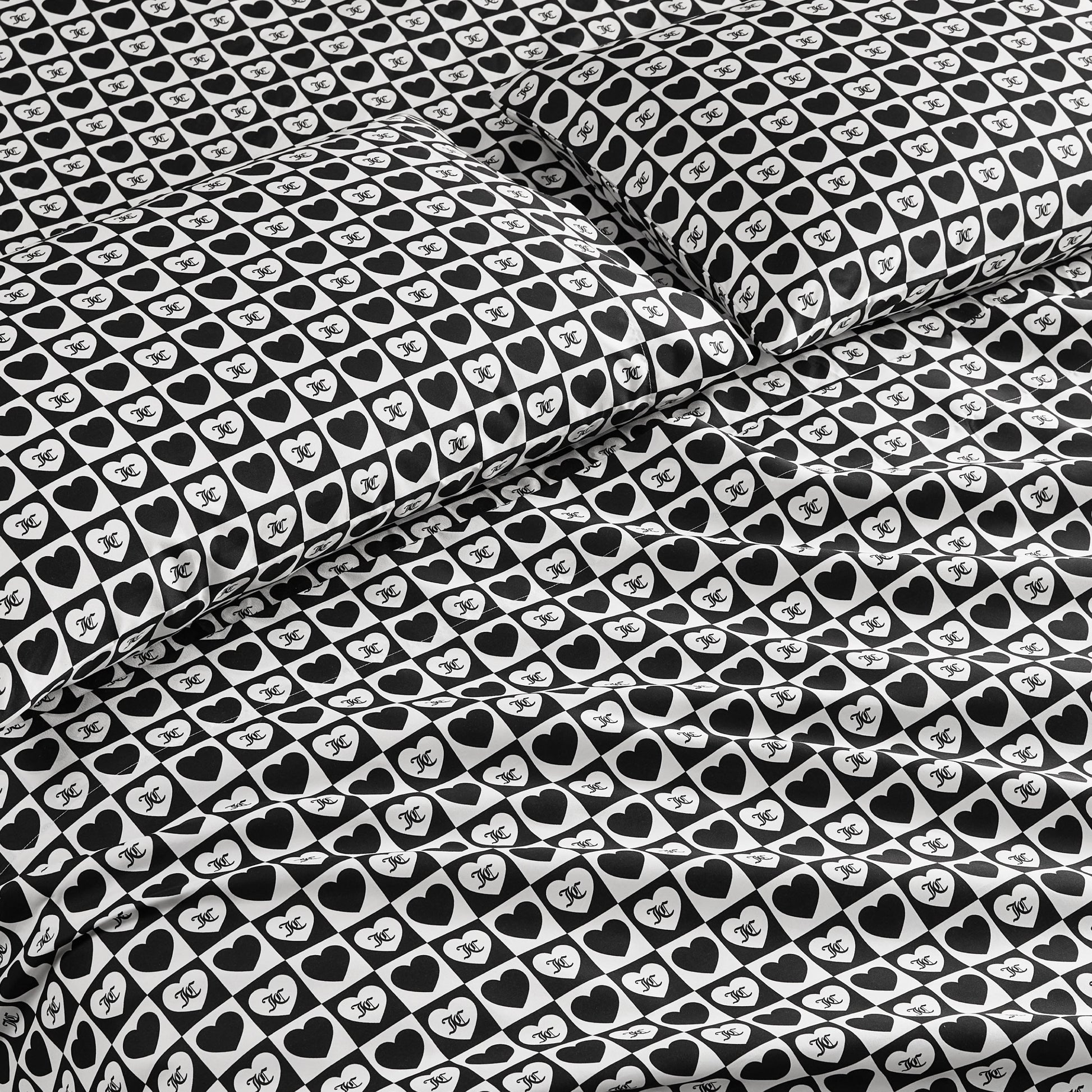 The Printed Microfiber Sheet Set features a bold black-and-white design with hearts and “NYC” text, creating a stylish look on the pillowcases and comforter—ideal for anyone who loves luxury bedding.