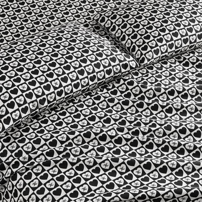 The Printed Microfiber Sheet Set features a bold black-and-white design with hearts and “NYC” text, creating a stylish look on the pillowcases and comforter—ideal for anyone who loves luxury bedding.