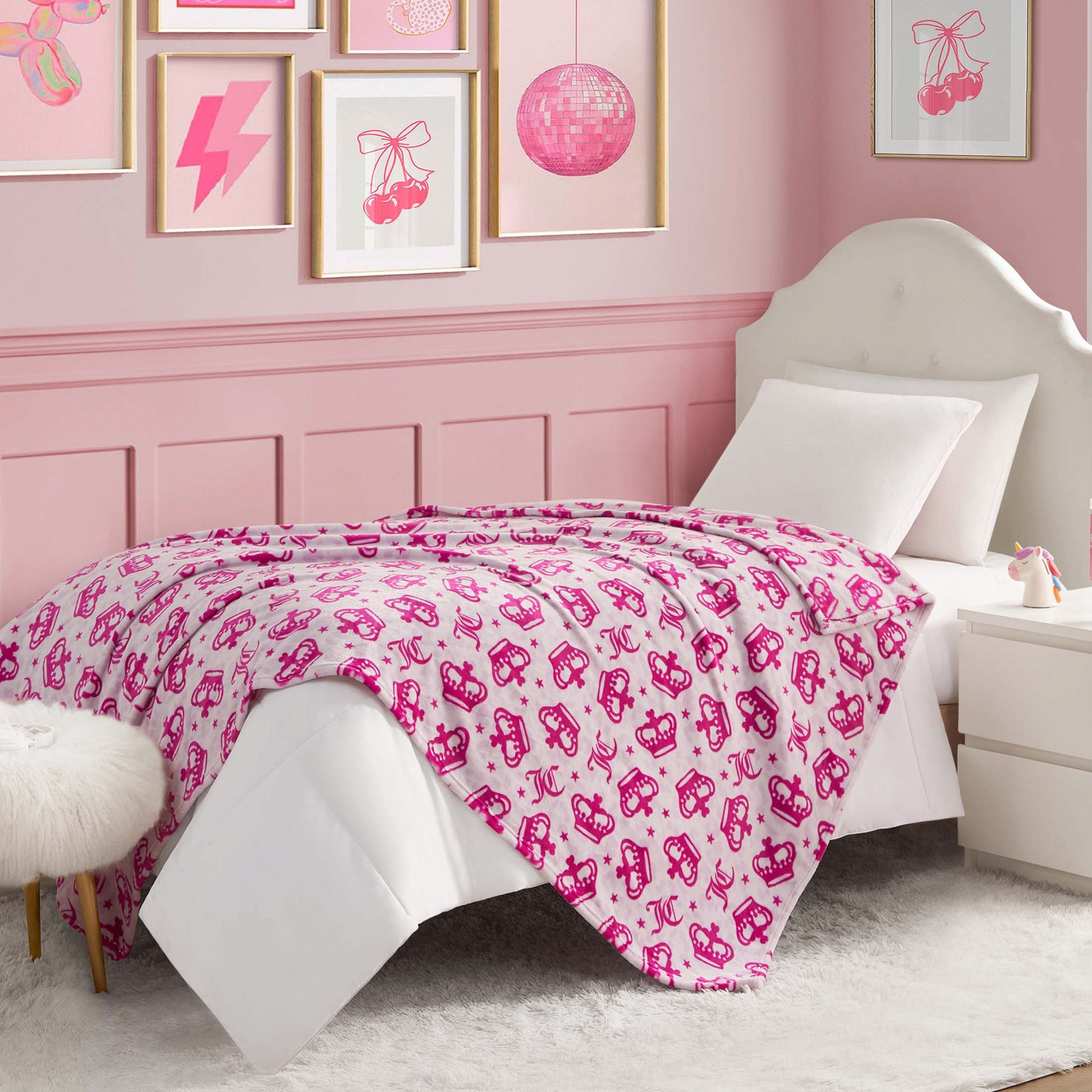 A pink-themed bedroom featuring a white bed, Kids Plush Throw Blanket for extra softness, a white nightstand, framed pink artwork, and coordinated pink and white decor for a cozy, stylish vibe.
