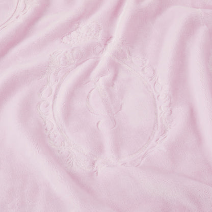 A close-up of the Plush Oversized Throw Blanket, 60" x 90", in soft light pink, featuring an embossed ornate oval frame with a script "J" in the center and a small crown above the frame.