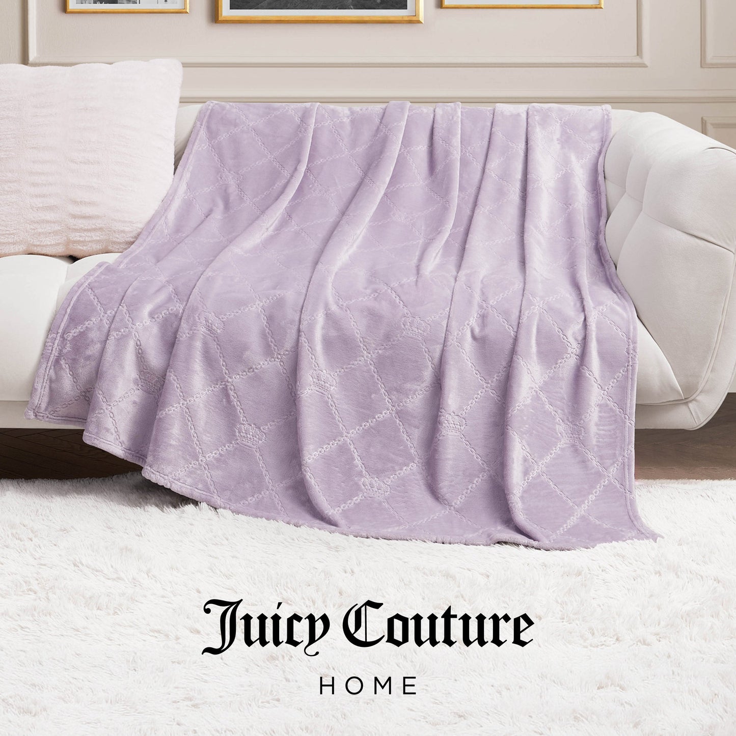 A light purple Plush Oversized Throw Blanket (60" x 90") with a quilted pattern is draped over a beige sofa next to a cream pillow on a white shag rug, with Juicy Couture Home at the bottom of the image.