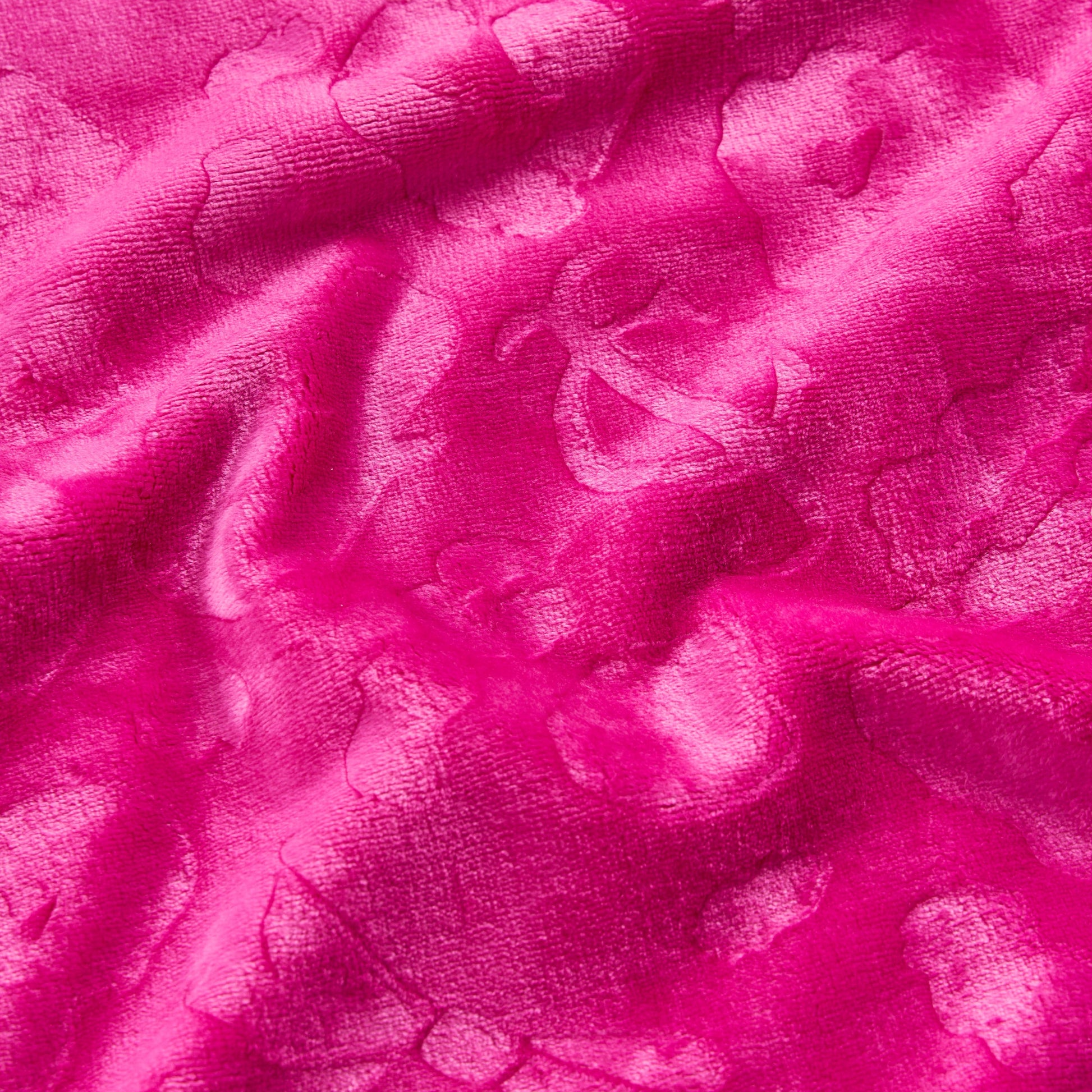 Close-up of the Plush Oversized Throw Blanket, 60" x 90", in bright pink with a subtle floral pattern. The ultra-soft, shiny textured fabric is gently wrinkled, highlighting captivating light and shadow variations.