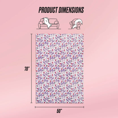 The Kids Plush Throw Blanket by Juicy Couture Kids features a colorful heart and paw print design, measures 70 x 50 inches, and is shown draped on a sofa and wrapped around a person. The ultra-soft material is ideal for cozy moments. Product Dimensions shown.