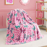 A Kids Plush Throw Blanket with pink leopard print and colorful butterflies is draped over a chair in a stylish pink room featuring gold and white shelves and framed wall art.