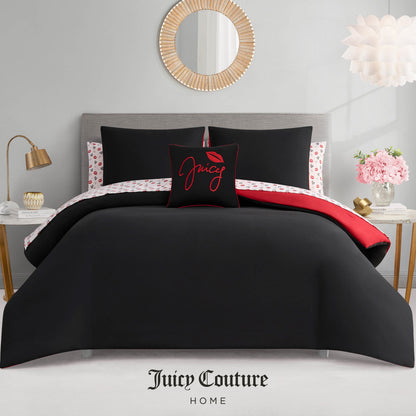 A modern bedroom highlights the Glam Girl Solid Reversible Bed in a Bag Bedding Set in black, red, and white with a decorative pillow featuring Juicy and red lips, styled against a gray headboard and neutral decor.