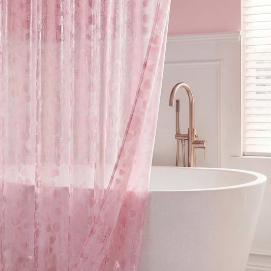 A white bathtub with a gold faucet sits behind a sheer pink PEVA Shower Curtain Liner in a softly lit bathroom with light pink walls and a window with white blinds.