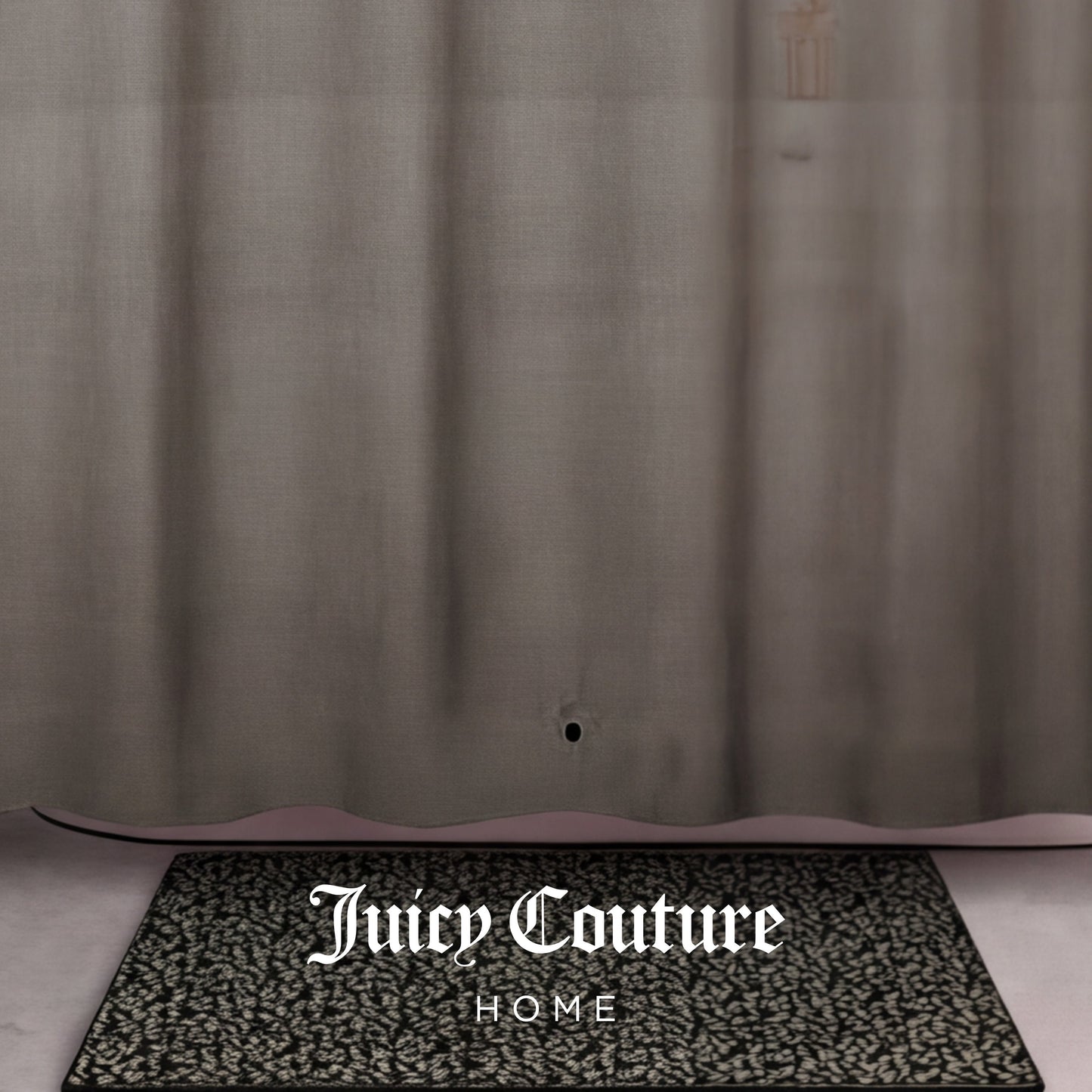 A patterned black and white doormat with Juicy Couture HOME sits in front of a sheer tan PEVA Shower Curtain Liner, which has a small hole near the bottom.