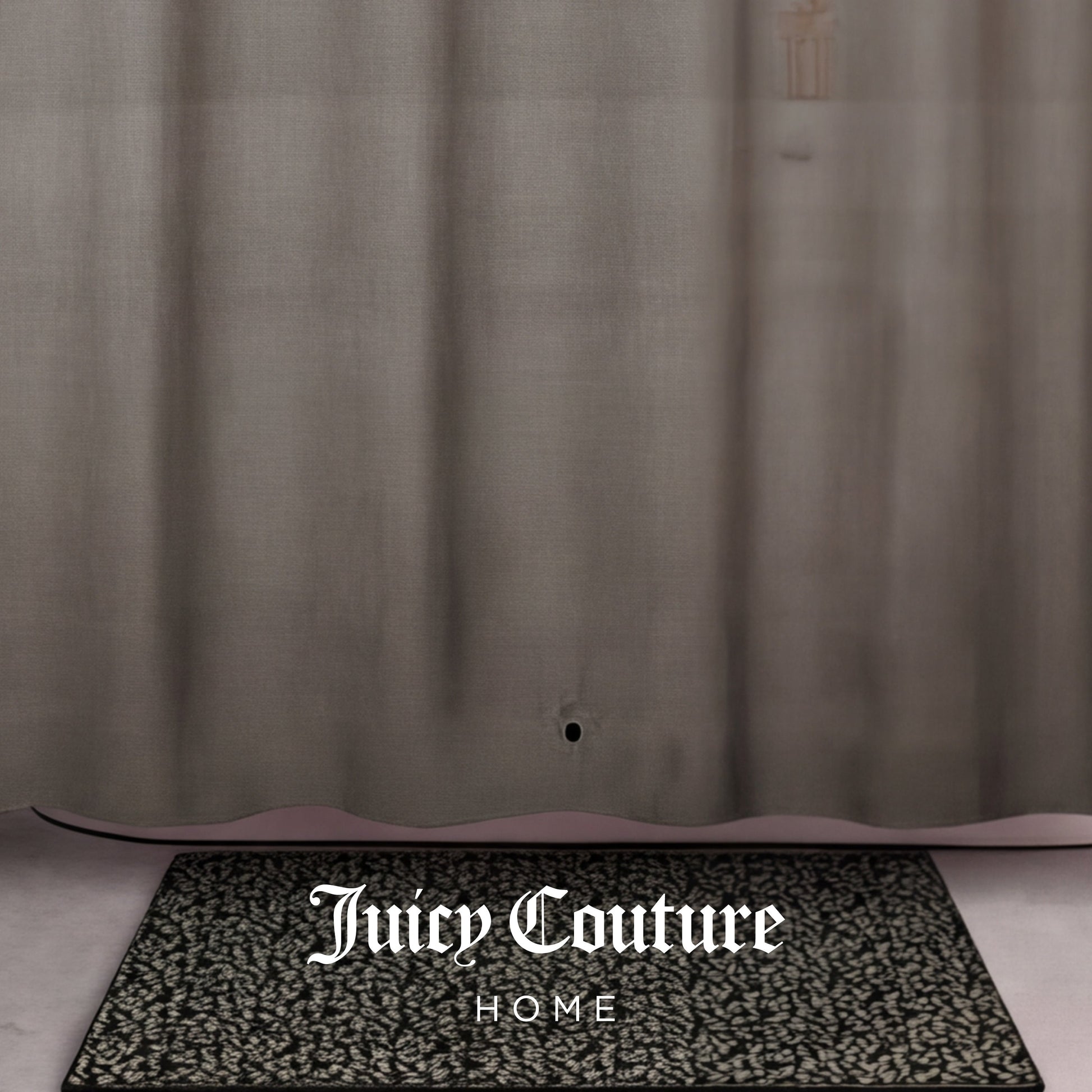 A patterned black and white doormat with Juicy Couture HOME sits in front of a sheer tan PEVA Shower Curtain Liner, which has a small hole near the bottom.