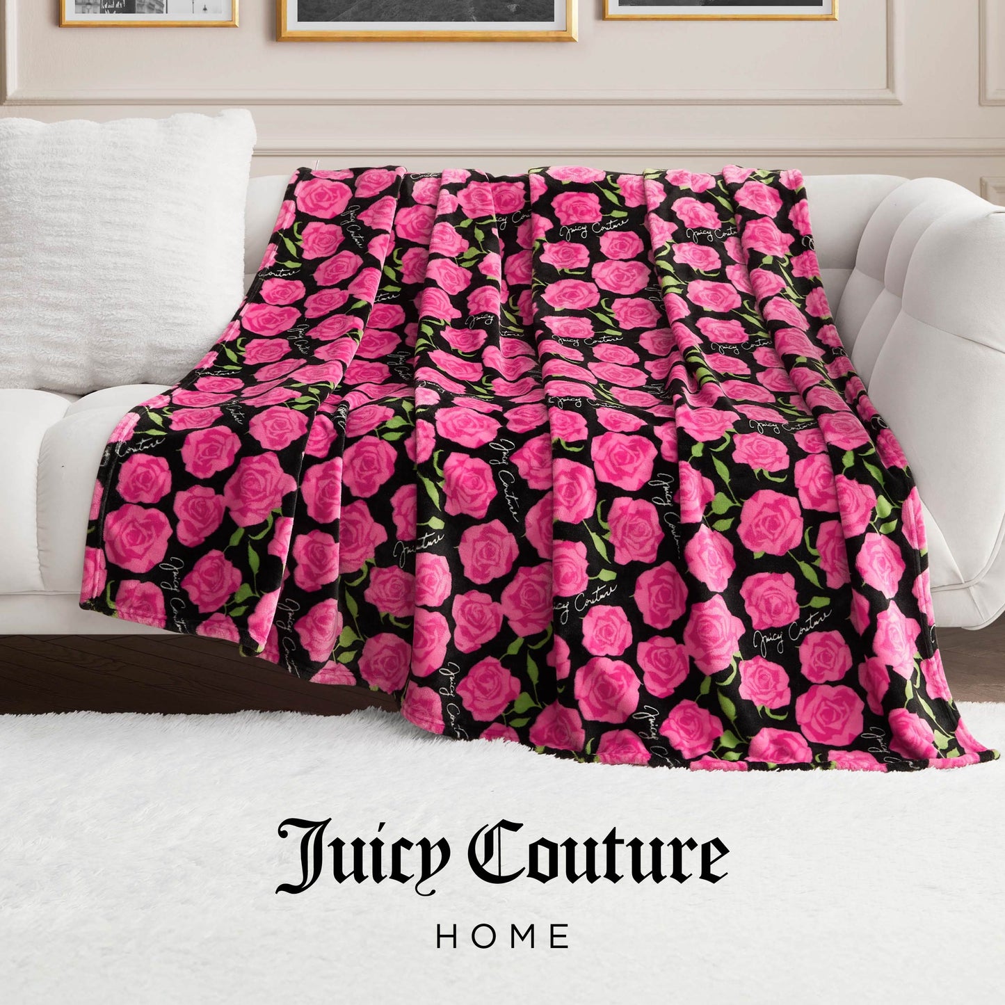 The Plush Oversized Throw Blanket, featuring a pink rose and green leaf design on black, is draped over a white sofa. "Juicy Couture Home" appears at the image's bottom.