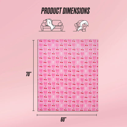 The Plush Oversized Throw Blanket by Juicy Couture is shown in a pink floral pattern, measuring 70x60 inches. Icons depict its ultra-soft feel, ideal for couches or wrapping around you. The light pink background enhances the cozy vibe.