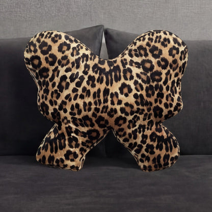 The Reversible Bow Decorative Pillow with a leopard print pattern rests on a dark gray sofa, complemented by matching cushions in the background.
