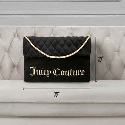 A Purse Decorative Pillow shaped like a black quilted Juicy Couture bag with a gold rope handle and bold gold branding (16" wide x 10" tall) rests on a tufted beige couch beside a trendy accent pillow.