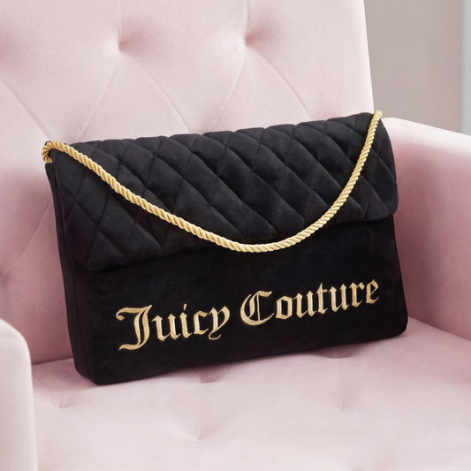 A Purse Decorative Pillow styled as a black quilted bag with gold lettering and a thick gold rope strap sits on a pale pink velvet chair, complemented by an accent pillow for a trendy, chic look.