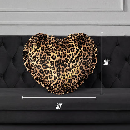 The Heart Shaped Decorative Pillow features leopard print, ruffled edges, and gold “JUICY” embroidery. Displayed on a black tufted sofa with white measurement arrows, it measures 20 inches in height and width.